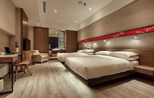 A modern hotel room with a large bed, a desk, and a chair.