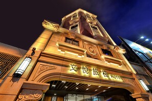 Fachada de hotel con detalles arquitectónicos ornamentales y señalización iluminada.