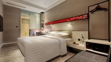 Quarto de hotel moderno com uma cama grande, mesas de cabeceira, uma TV e um painel decorativo vermelho.