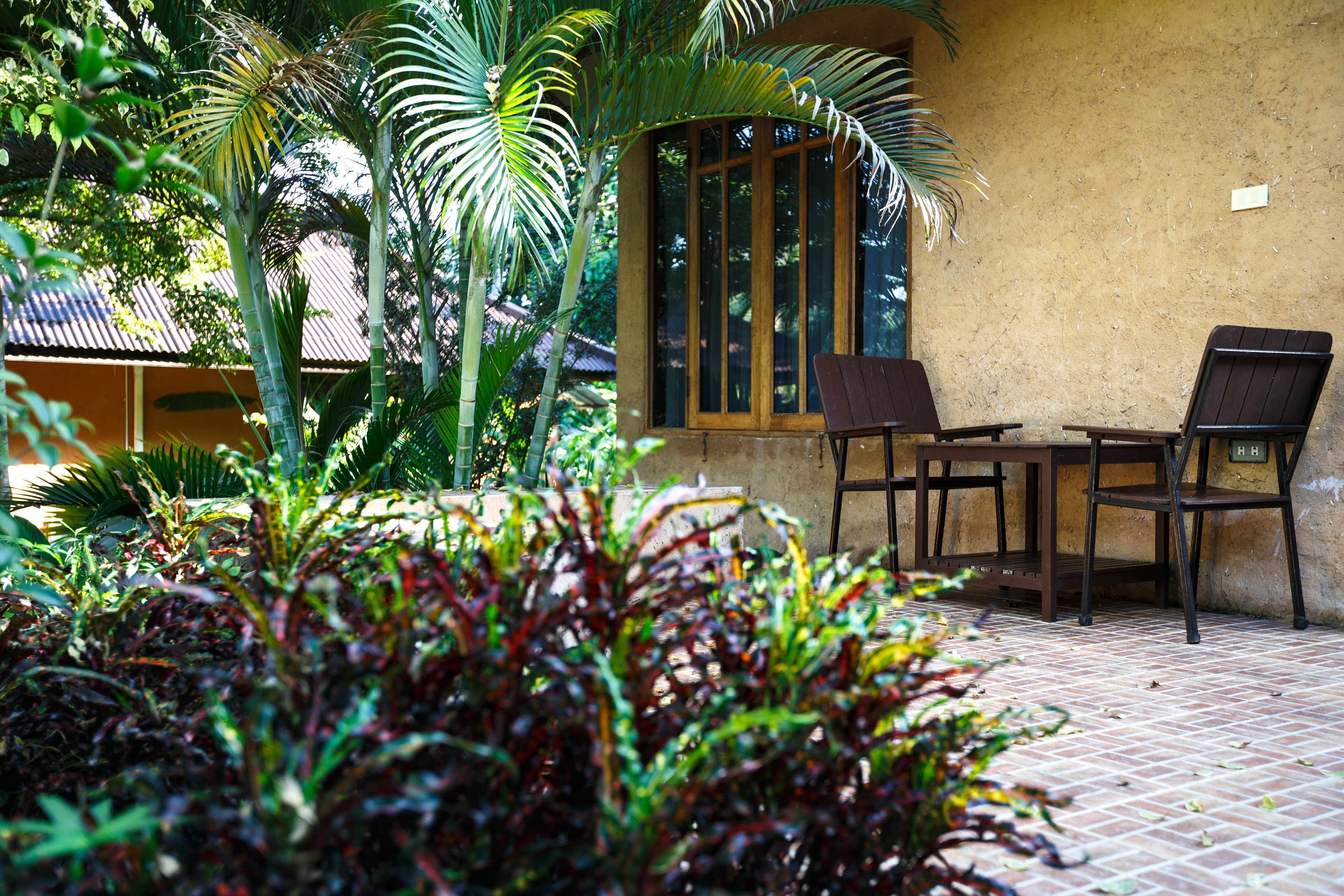 A patio area with a brick floor, two wooden chairs, and a table.