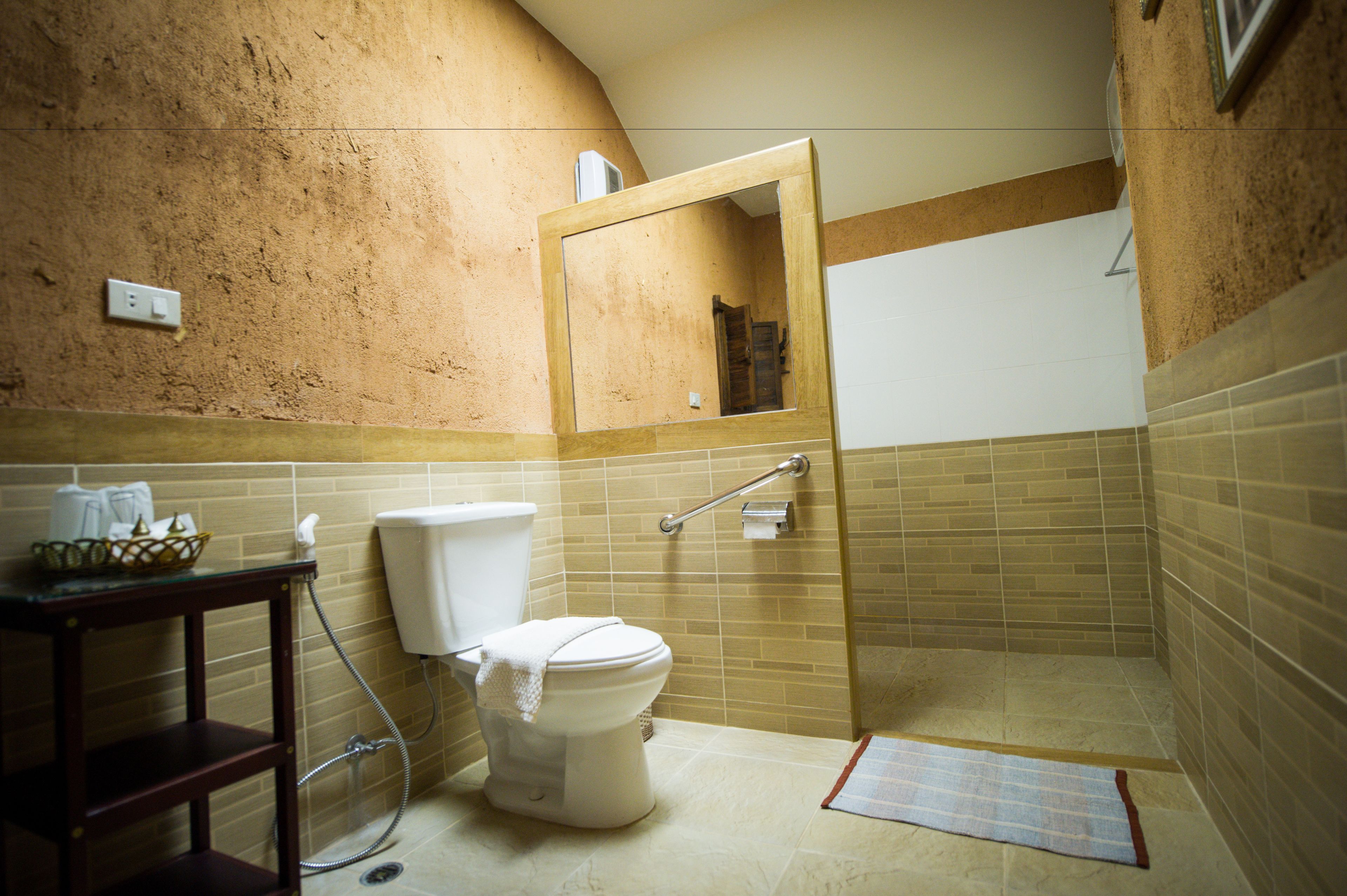 Une salle de bain comprenant des toilettes, un lavabo, un miroir et un espace douche.