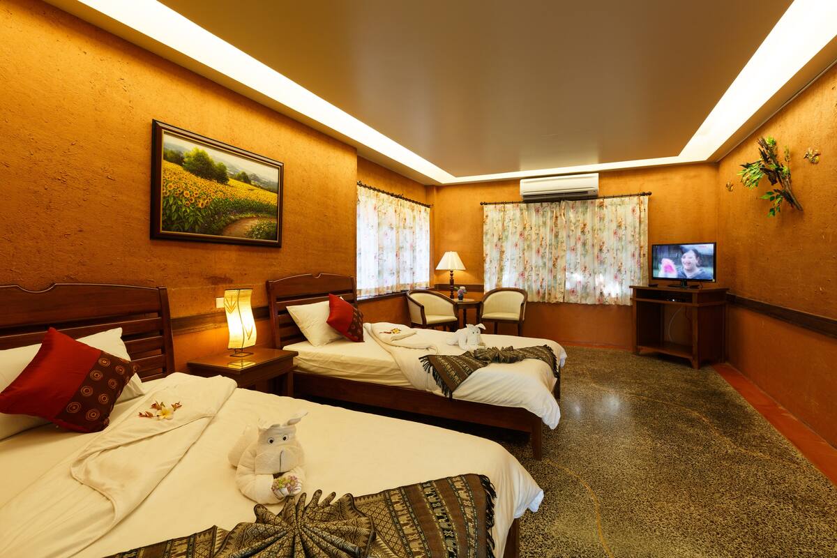 A hotel room with two beds, a television, a desk, and a chair.