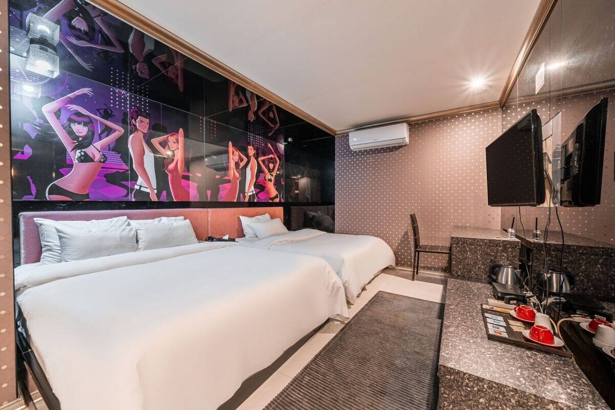 A hotel room with a large bed, a small desk area, and a wall-mounted TV.