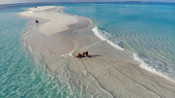 Vue aérienne d’une plage aux eaux turquoise et limpides et au rivage sablonneux.