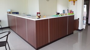 A reception desk with a clock, a small shrine, and a sign indicating check-in and check-out times.