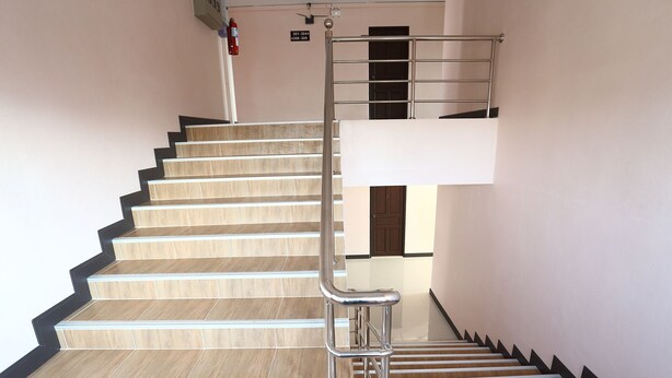 A staircase with wooden steps and metal handrails, leading to a landing with a door.