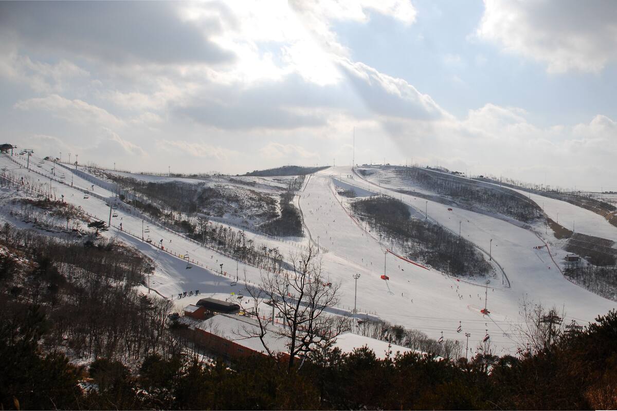 A snow-covered ski slope with ski lifts and a clear sky.