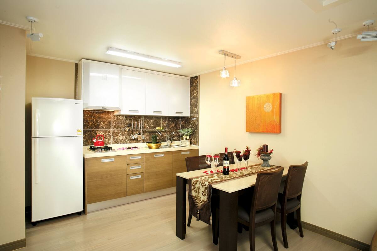 A modern kitchen with white cabinets, a marble backsplash, and a dining area with a table set for four.