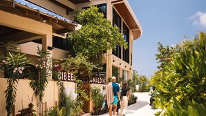 A modern hotel with a sign reading "CIBEEMALDIVES" and a covered outdoor area with plants and a motorcycle. - Bibee Maldives (Dhiffushi)