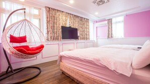 Une chambre à coucher avec un lit, un fauteuil suspendu, une télévision et une fenêtre avec des rideaux.