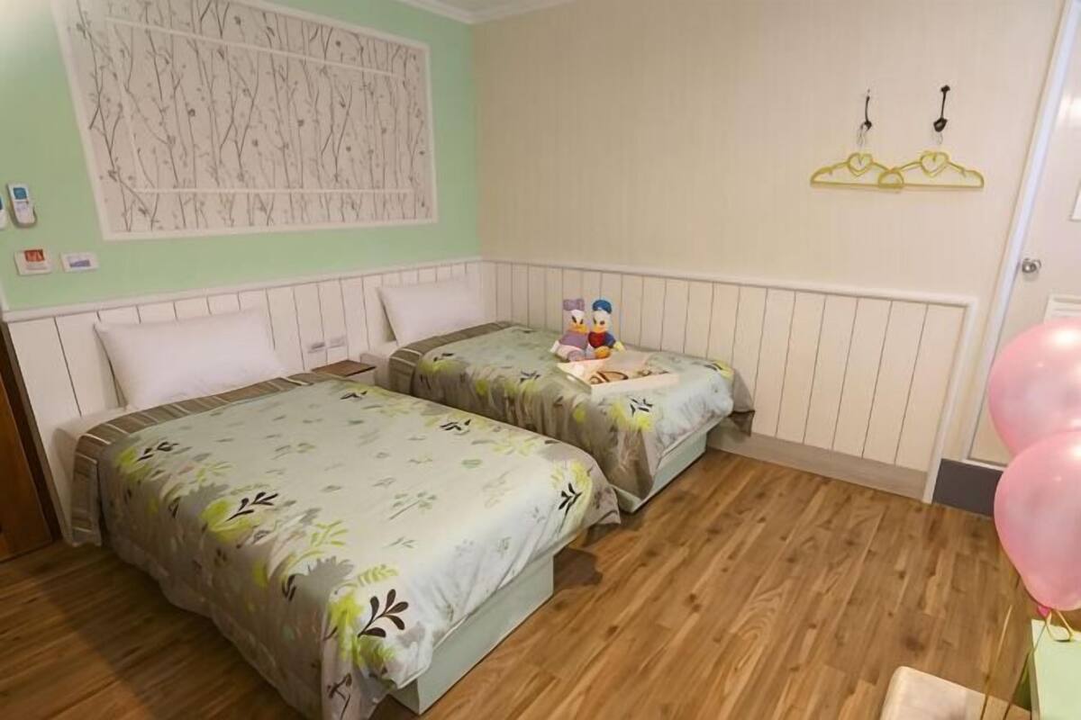 Una habitación con dos camas, un radiador, una pared decorada y una puerta adornada con globos.