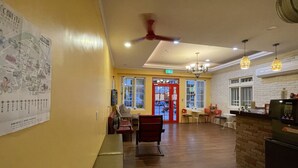 Un hall d’entrée spacieux avec un plancher en bois, une porte rouge et un espace détente comprenant des chaises et un banc.
