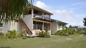 Una casa de dos pisos con un balcón, una escalera y un jardín bien cuidado.