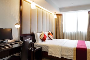 A hotel room with a bed, a desk with a computer, and a chair. - New World Hotel (Guangzhou)