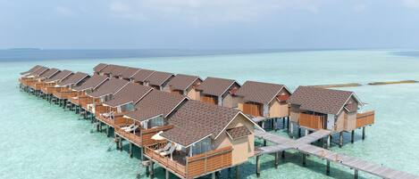 A row of overwater bungalows connected by a wooden walkway.