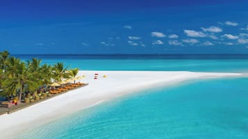 Un complexe hôtelier de bord de mer avec du sable blanc, une eau turquoise et des palmiers.