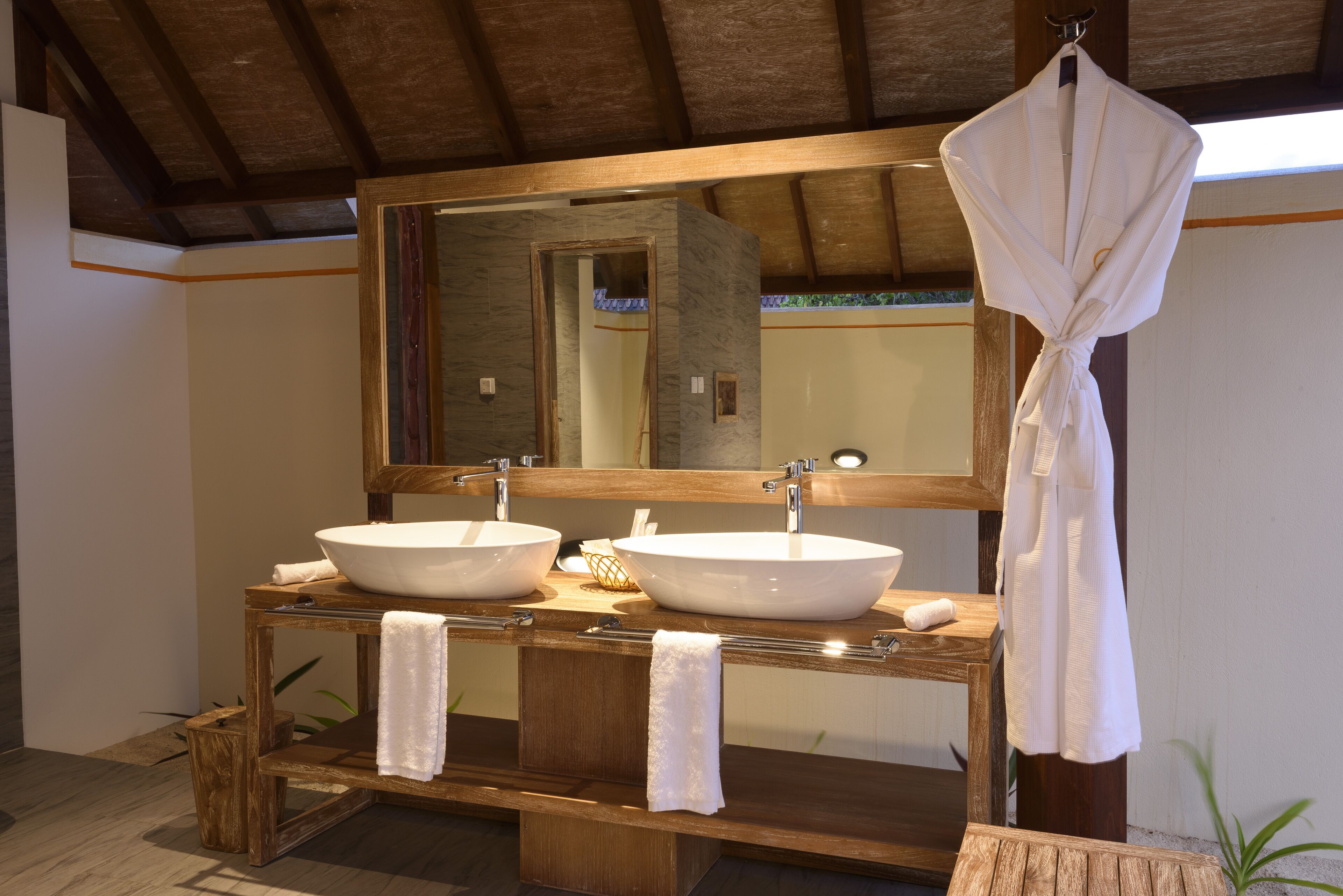 Un baño con dos lavamanos grandes, tocador de madera y un espejo amplio.