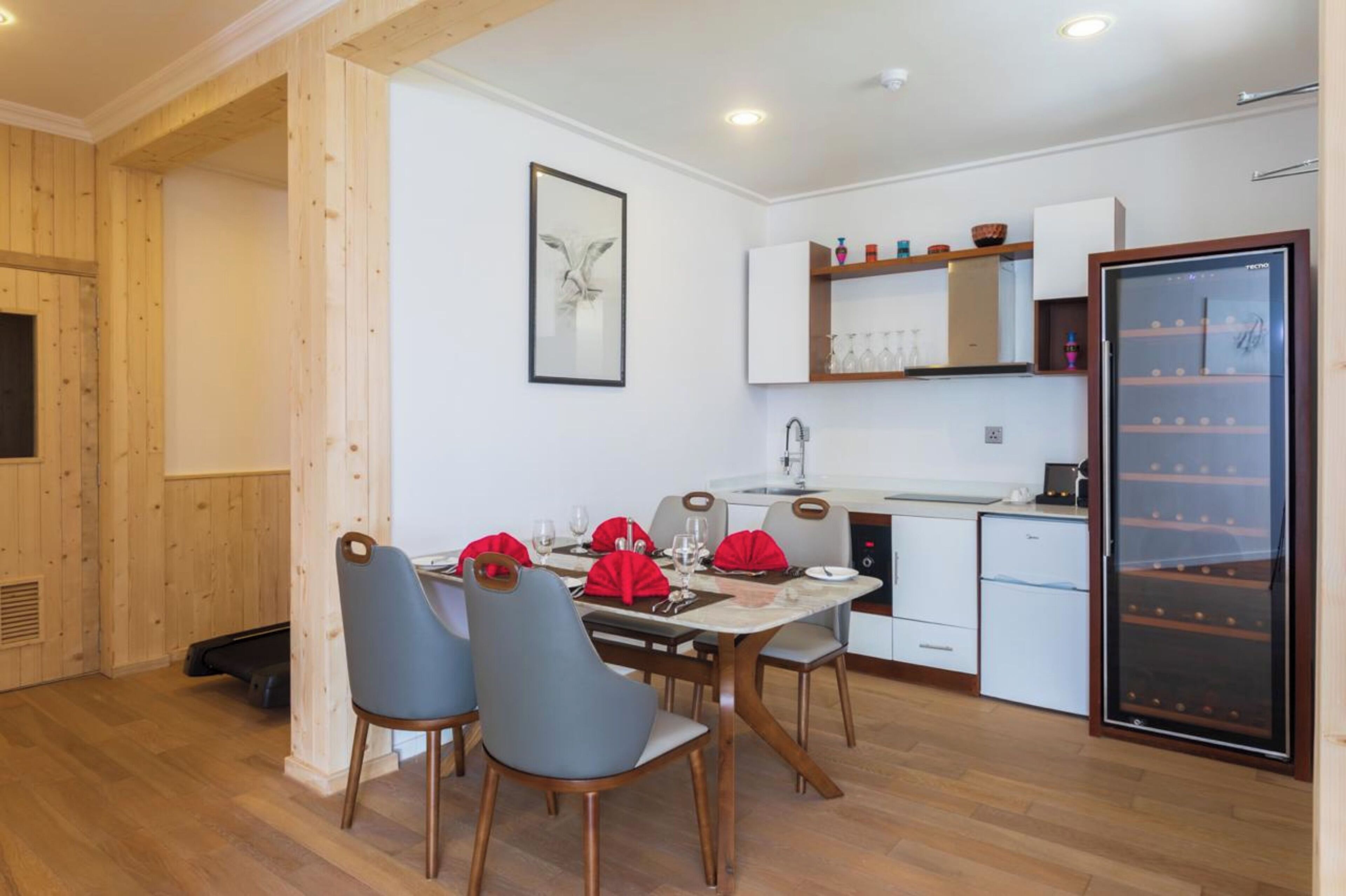 A compact kitchen with a dining area, wooden walls, a refrigerator, and a sink.