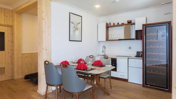 A compact kitchen with a dining area, wooden walls, a refrigerator, and a sink.