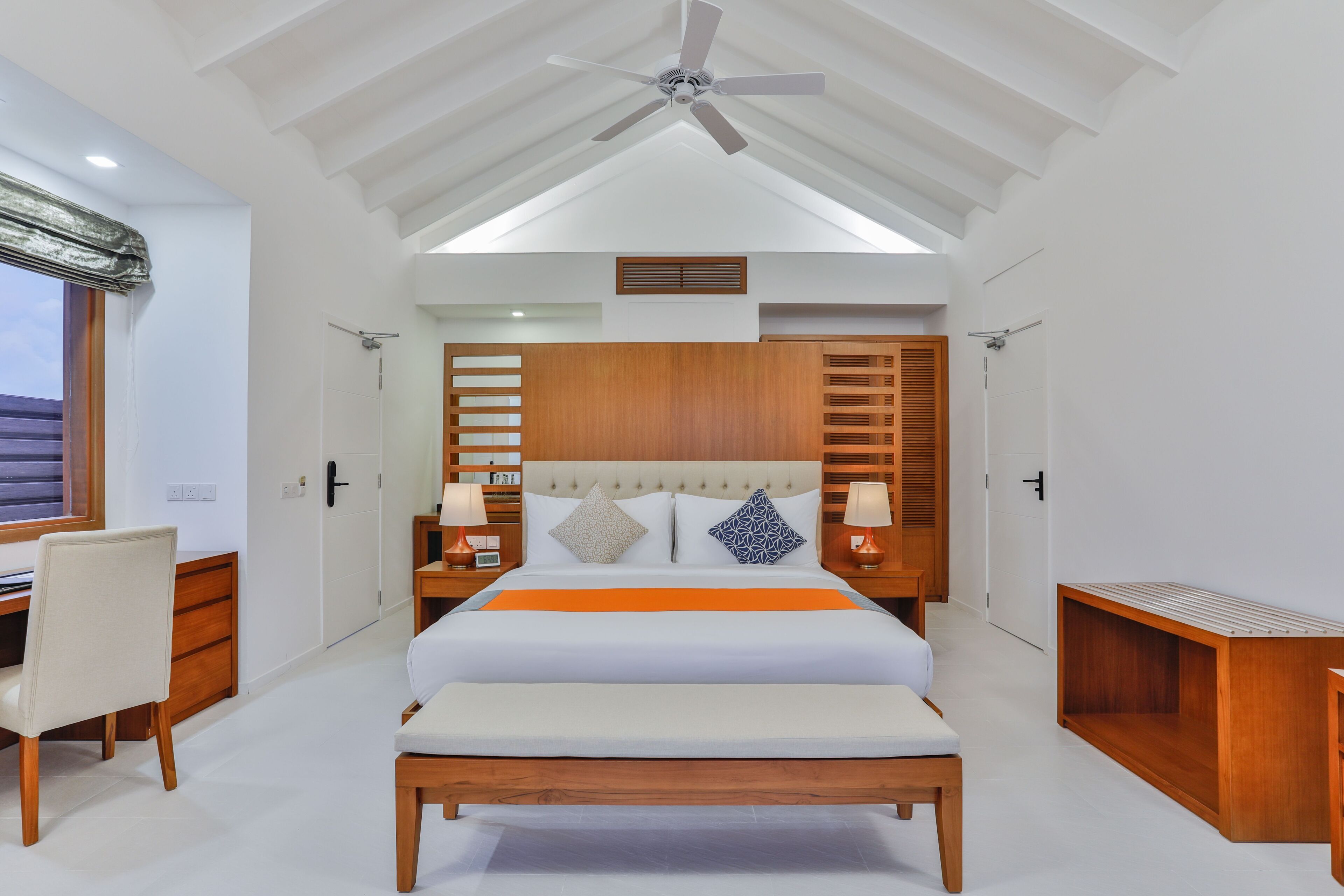 Un dormitorio con cama, mesitas de noche, escritorio y silla.
