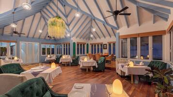 Un restaurant doté de hauts plafonds, de poutres apparentes et offrant différents types de sièges, notamment des fauteuils confortables et des tables.
