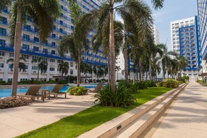 A hotel with a pool area, palm trees, and a well-maintained lawn.