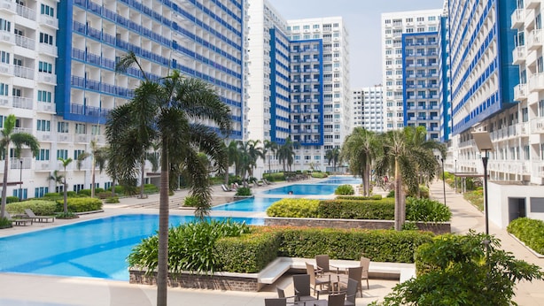 Un hôtel moderne composé de plusieurs immeubles de grande hauteur, doté d’une piscine centrale et entouré de verdure.