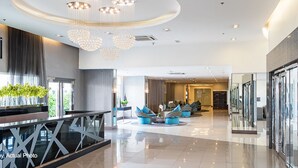 Un hall d’entrée moderne avec une cloison en verre, des espaces de détente et un lustre.