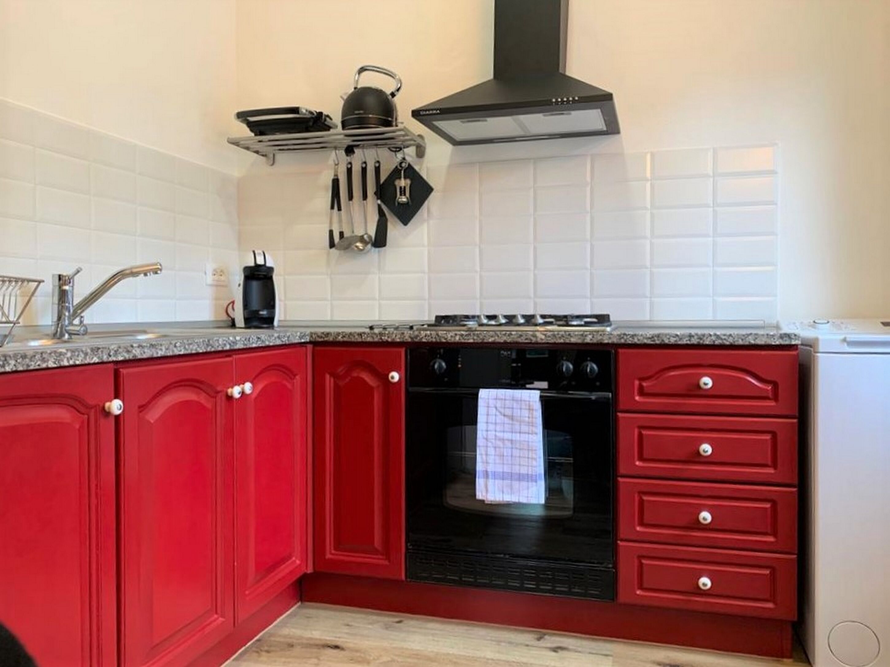 A kitchen with red cabinets, a black stove, and a microwave.