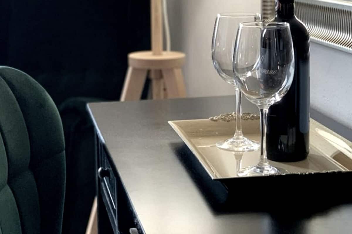 A table with a bottle and two glasses, a chair, and a stool.
