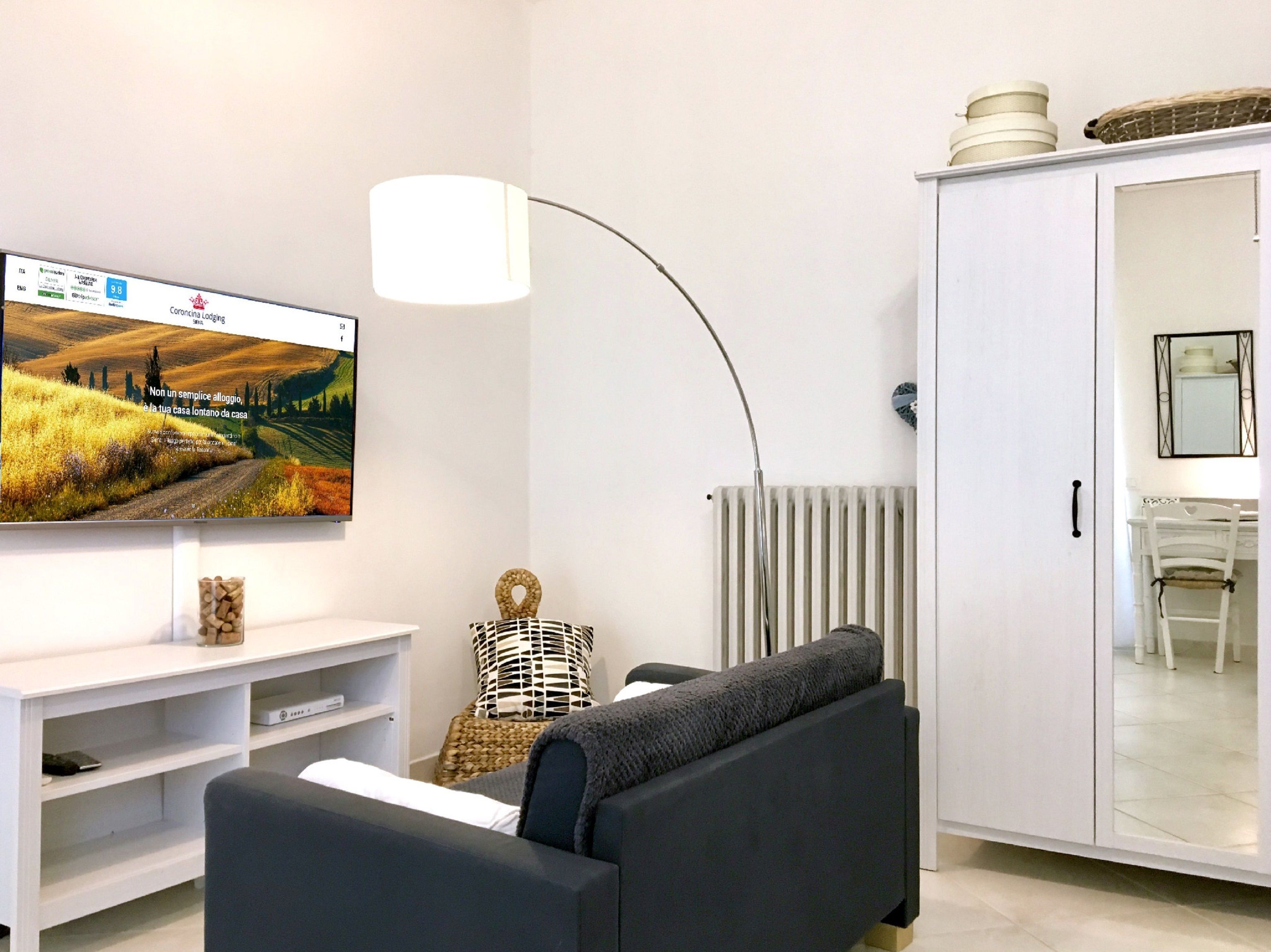Un salon moderne comprenant un téléviseur à écran plat, un canapé, une lampe, un radiateur et un meuble.