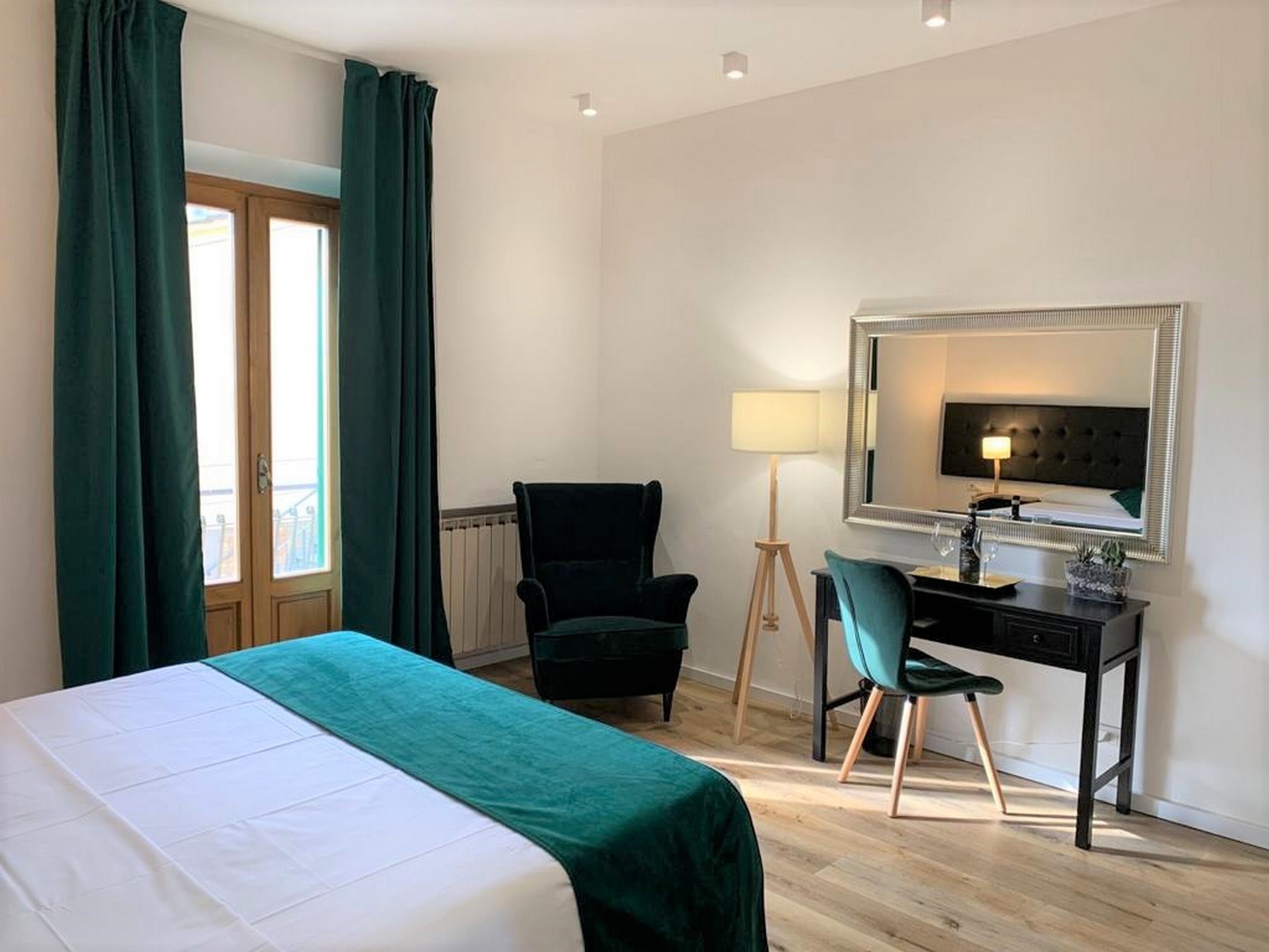 Ein Hotelzimmer mit einem Bett, einem Schreibtisch mit Stuhl, einer Lampe und einem großen Spiegel.