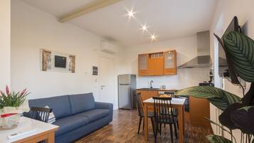 Een knus leefruimte met een kitchenette, een eethoek en een bank.