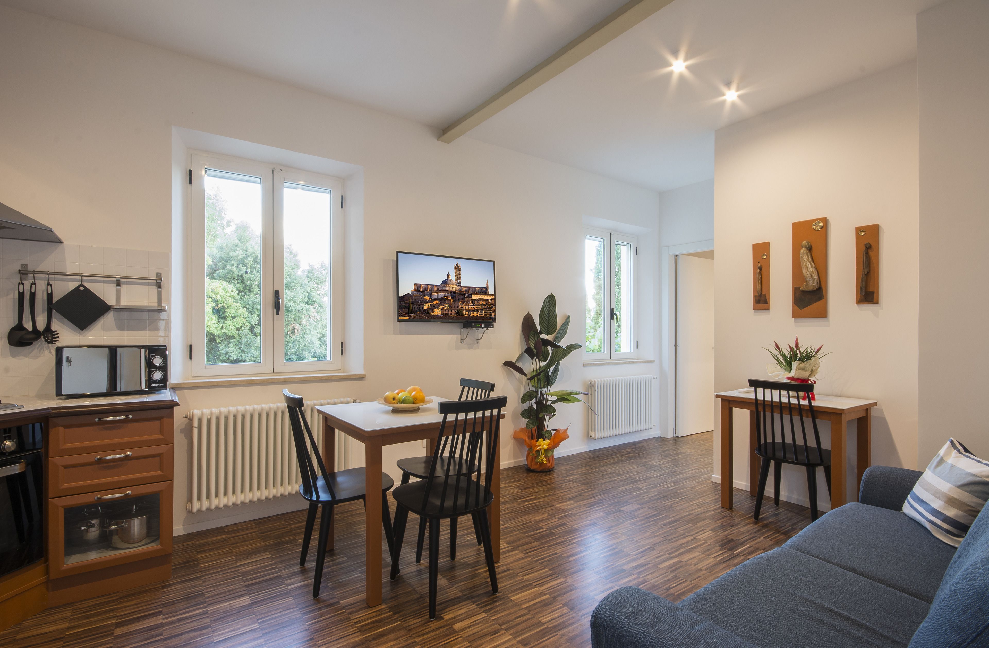 A modern kitchen with a built-in microwave, a dining table with chairs, and a large window.