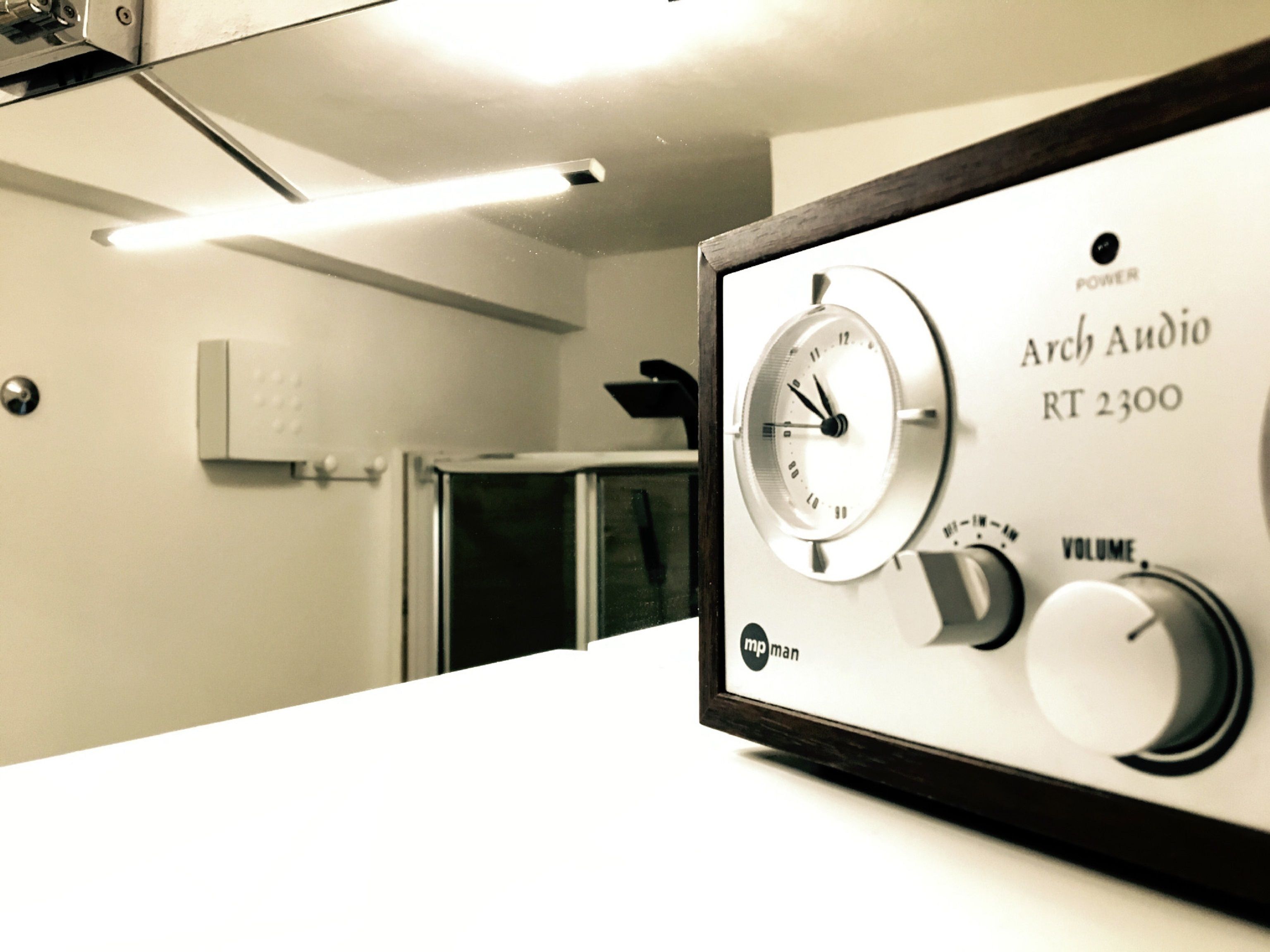 Rádio antigo com relógio, controle de volume e nome da marca "Arch Audio RT 2300".