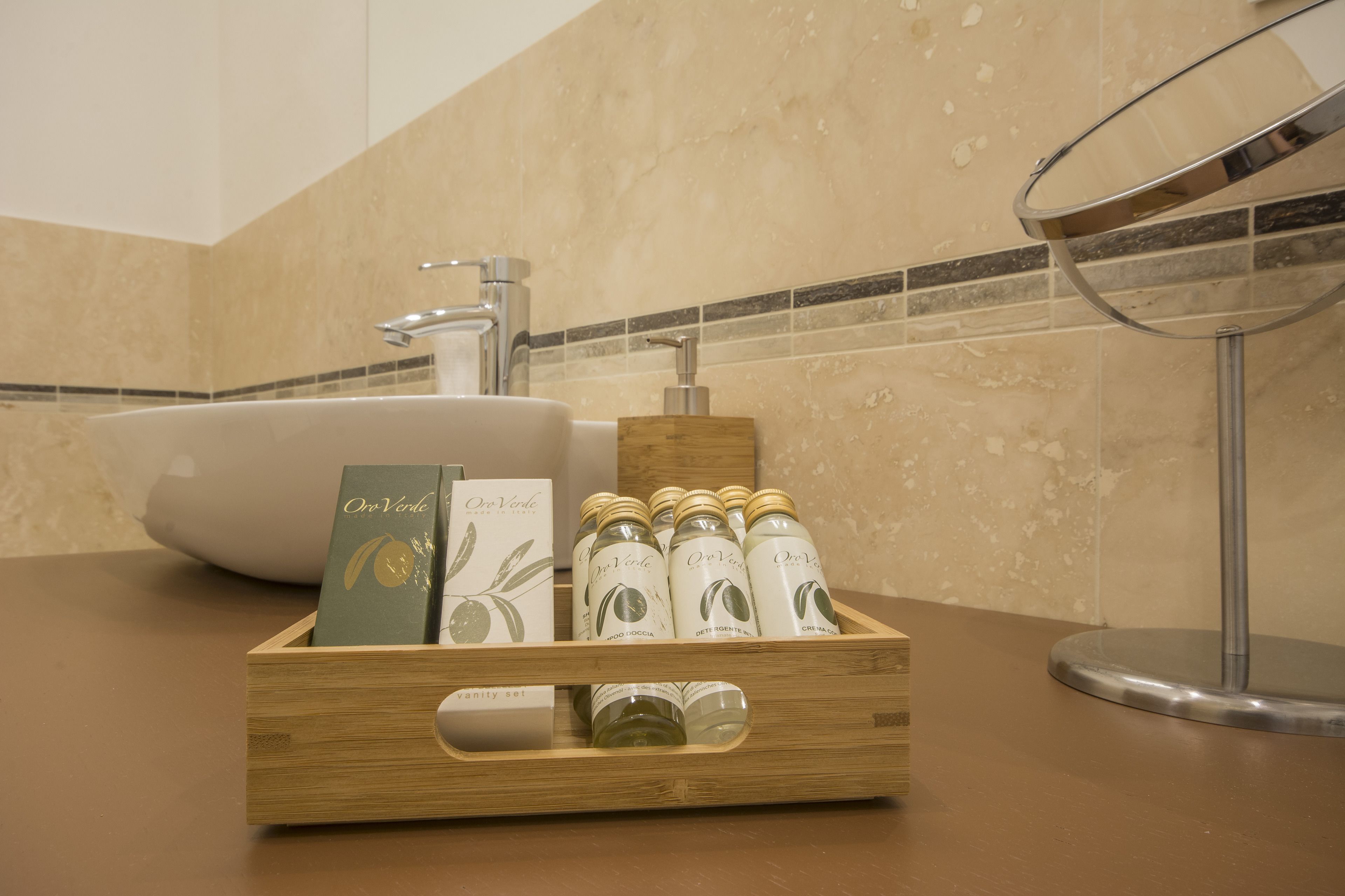 Una caja de madera con botellas y una tarjeta sobre una encimera de baño.