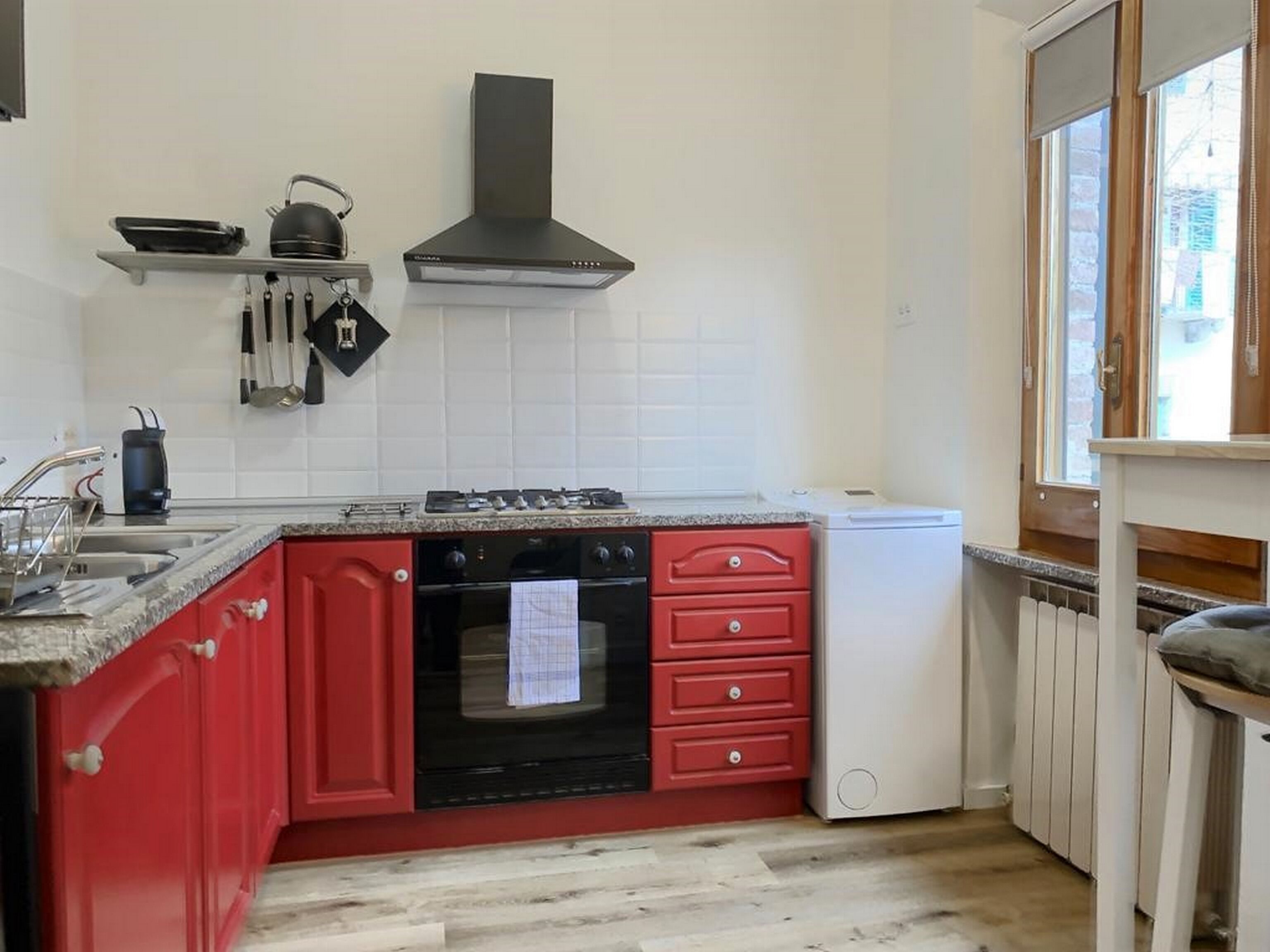 A kitchen with red cabinets, a black stove, and a white refrigerator.