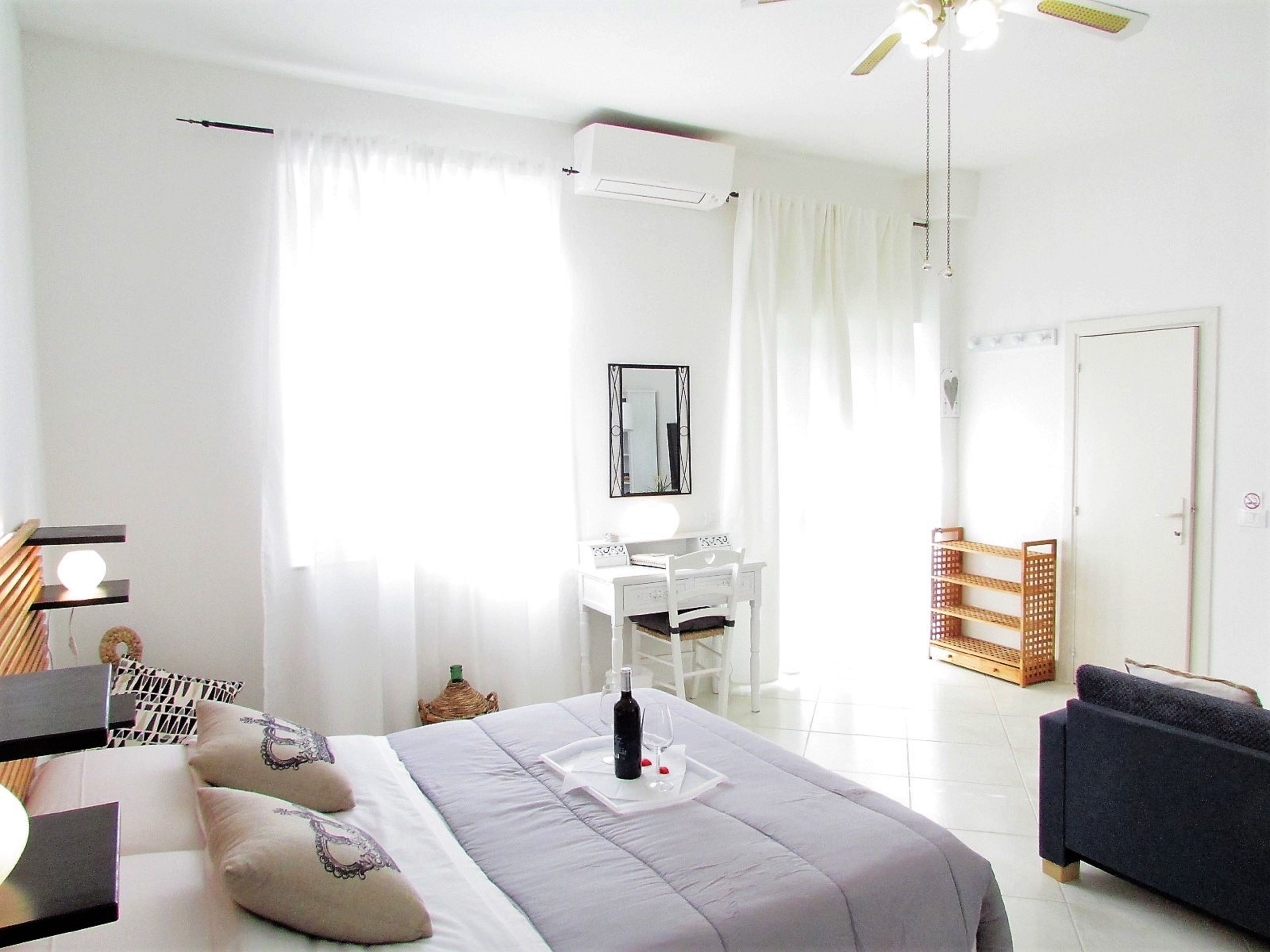 A hotel room with a bed, a desk, a chair, a wardrobe, and a door.