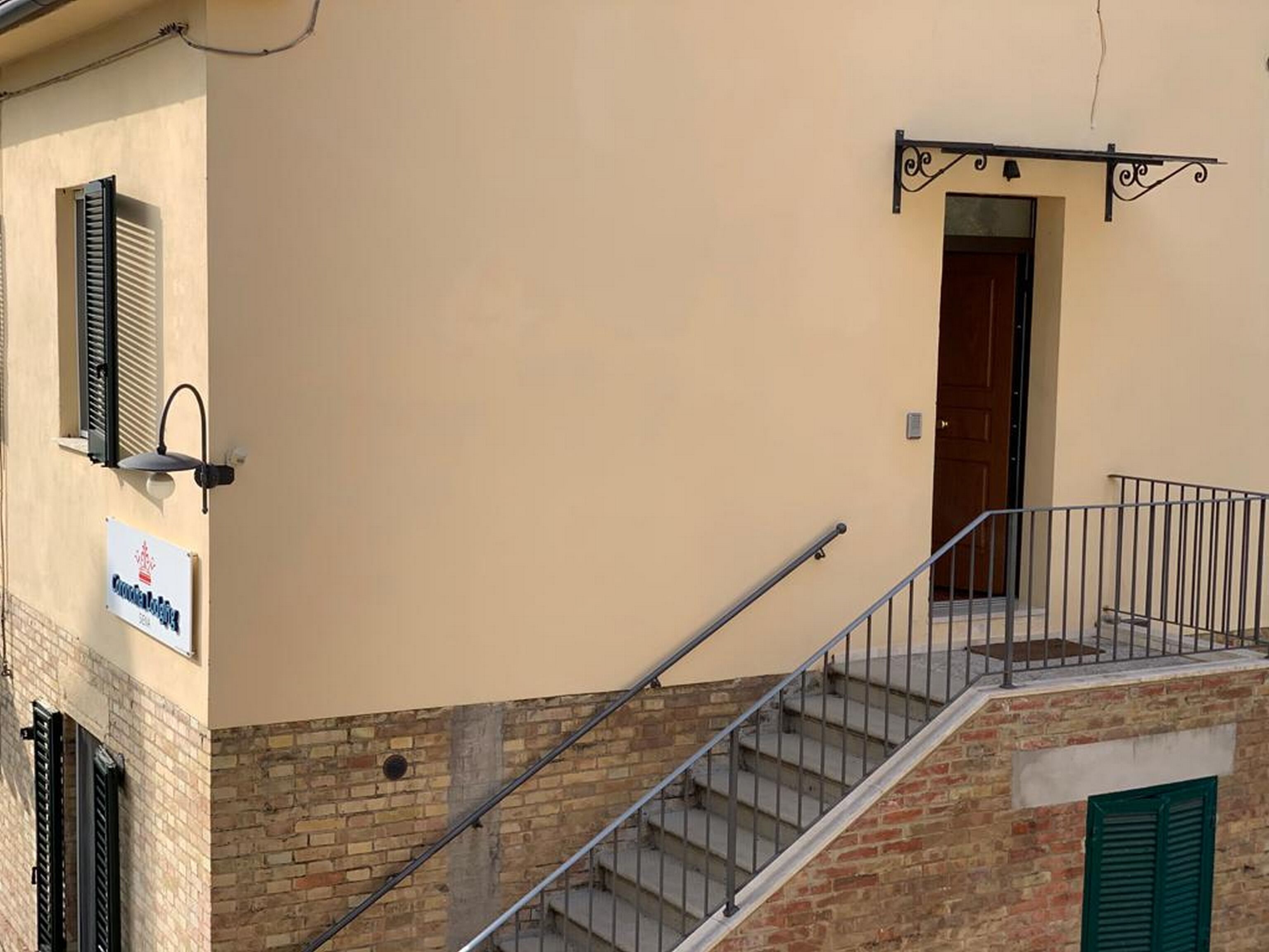 Un edificio con una escalera que lleva a una plataforma, una puerta y un letrero en la pared.