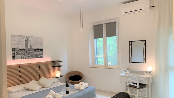 Un dormitorio con cama, mesita de noche y ventana con vistas a follaje.