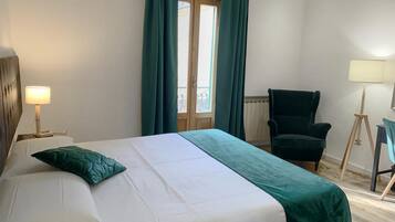 Ein Hotelzimmer mit Bett, Stuhl, Lampe und einem fenster mit Vorhängen.