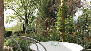 A white metal table with a glass ashtray, surrounded by lush greenery and flowering plants.
