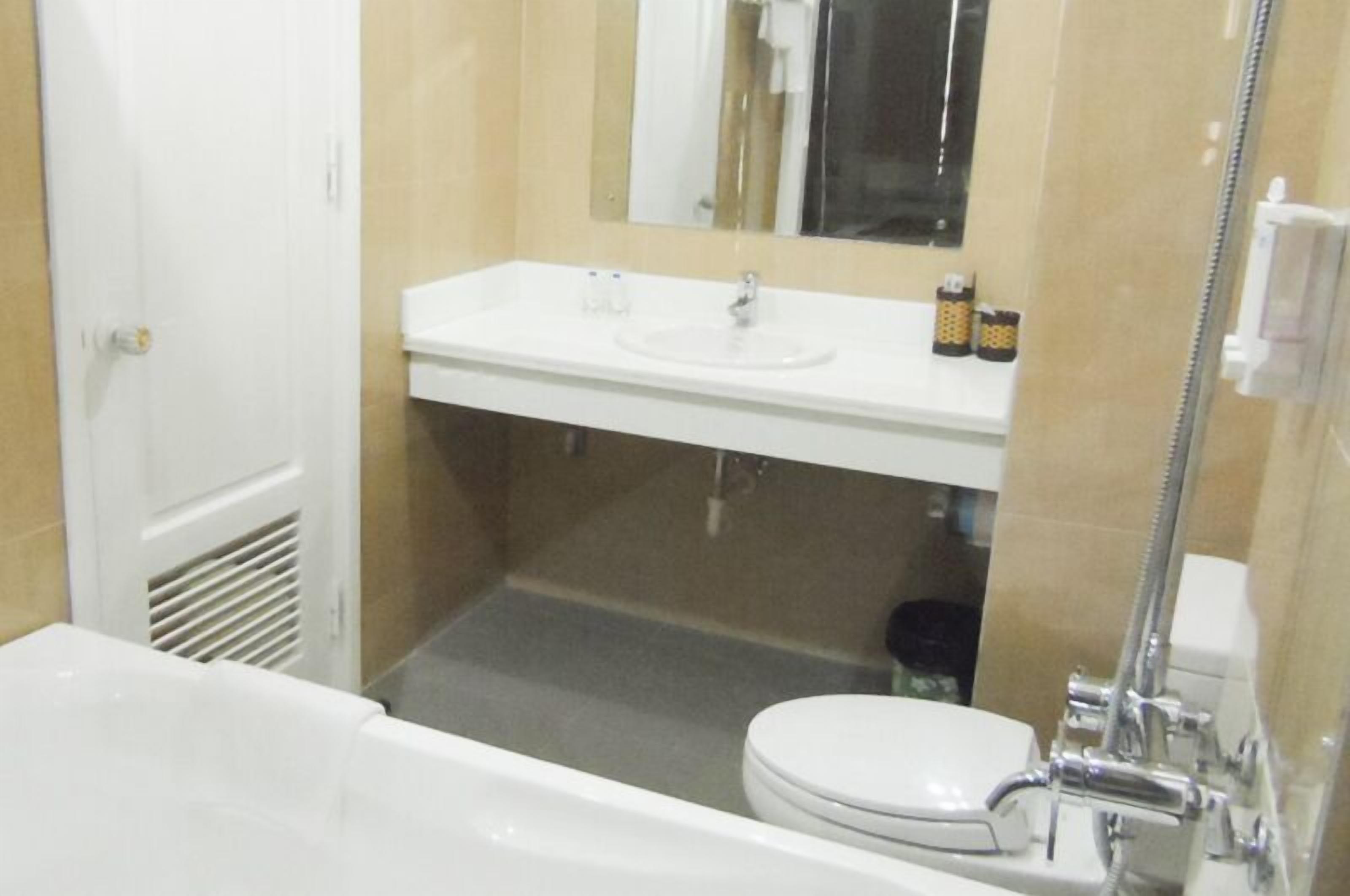 A bathroom with a white sink, mirror, and toilet.