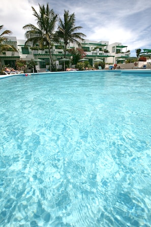 Ein klares Schwimmbecken mit Blick auf ein Hotel im Hintergrund.
