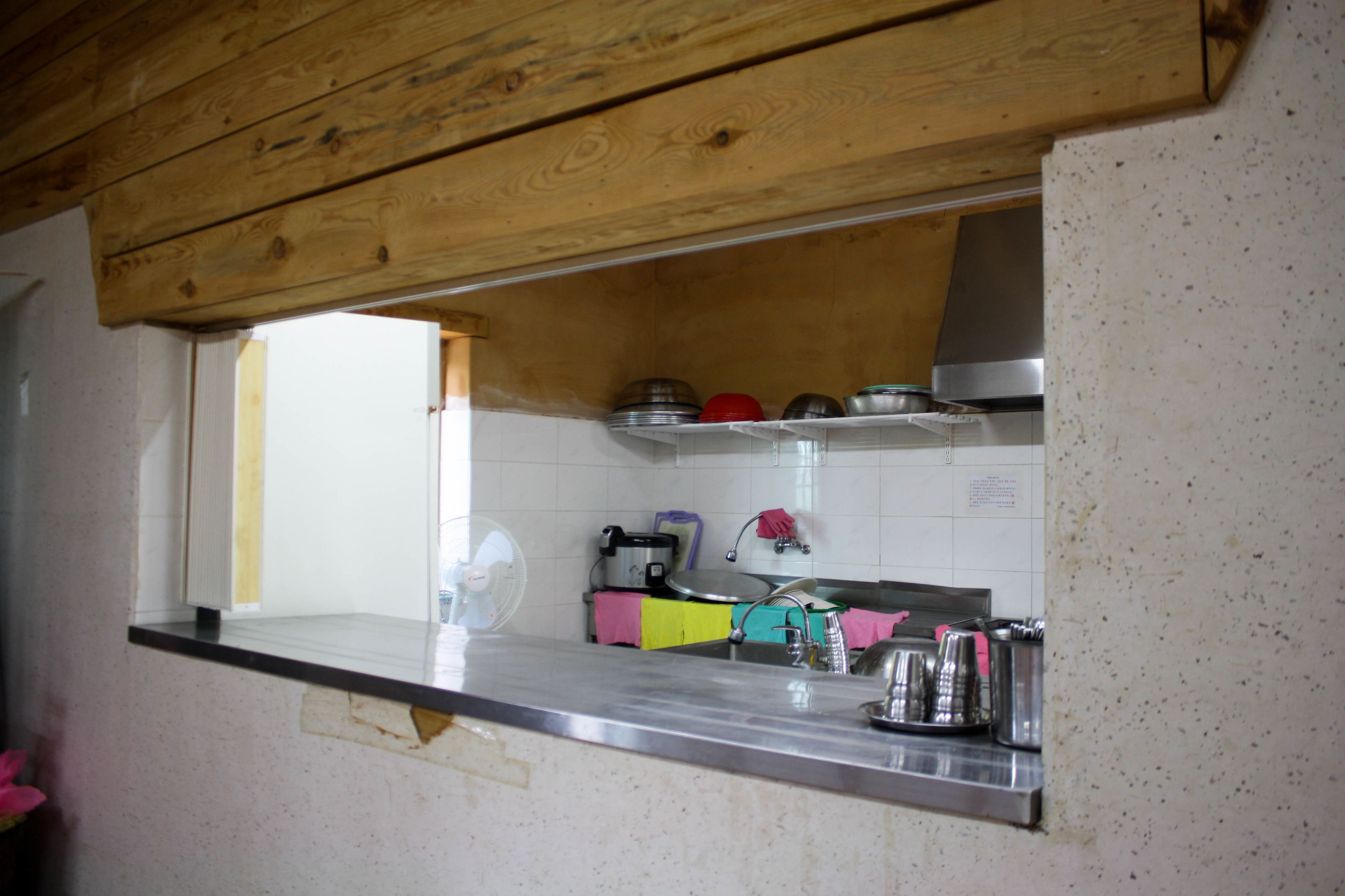 A kitchen with a wooden ceiling, a stainless steel countertop, and a window.