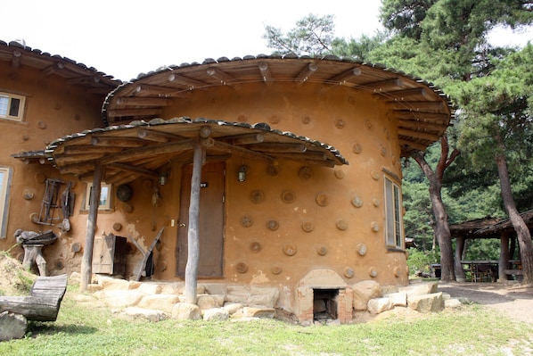 Ein rustikales Gebäude mit kreisförmigem Design, einer Holztür und einem Steinkamin.
