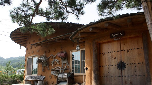 Un bâtiment rustique en bois, doté d’une grande porte en bois, d’une fenêtre et d’une enseigne au-dessus de la porte.