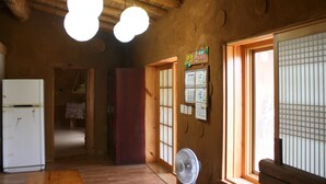 Une pièce de style japonais traditionnel, avec des poutres en bois, un éventail, un réfrigérateur et une porte coulissante de type shoji.