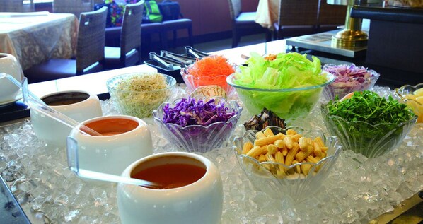 Una mesa de buffet con diversos alimentos y aderezos sobre hielo.