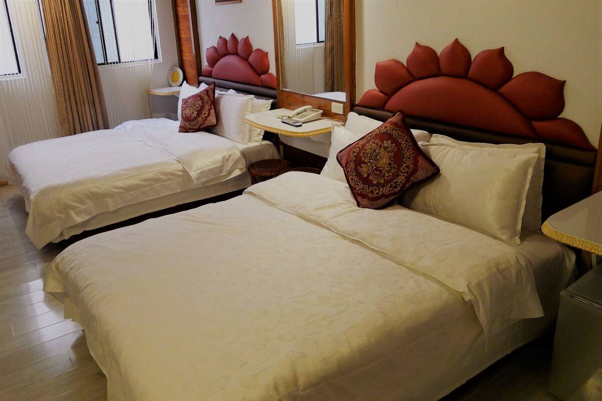 Habitación de hotel con dos camas, una mesita de noche con teléfono y un espejo.